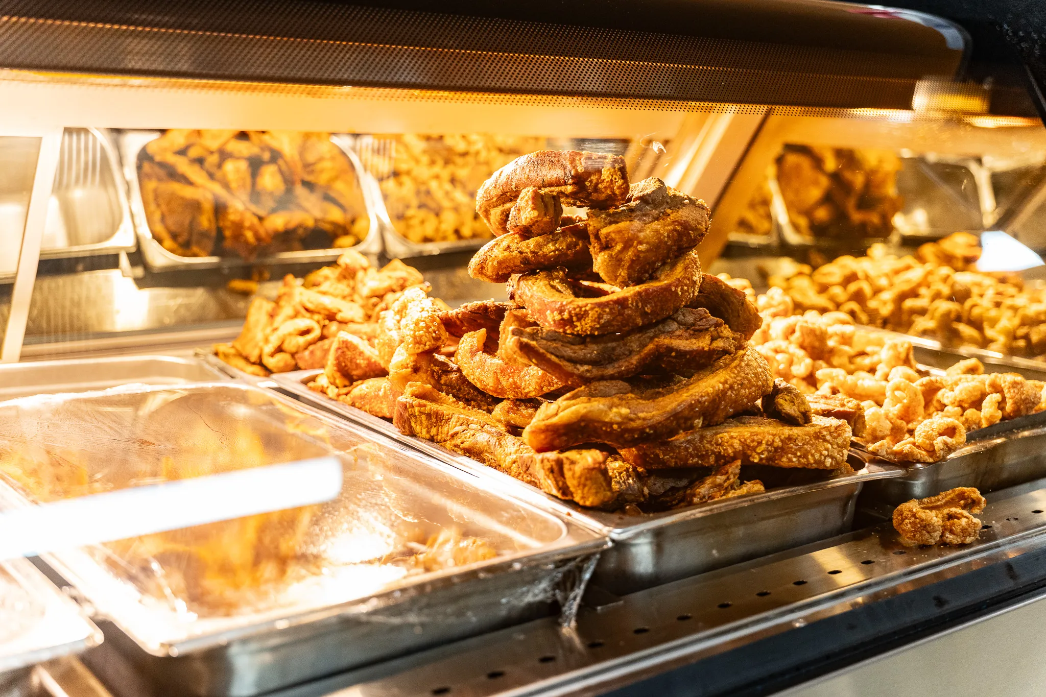 Tray of freshly fried chicharrón and golden specialties at the Carnicería 99 hot deli