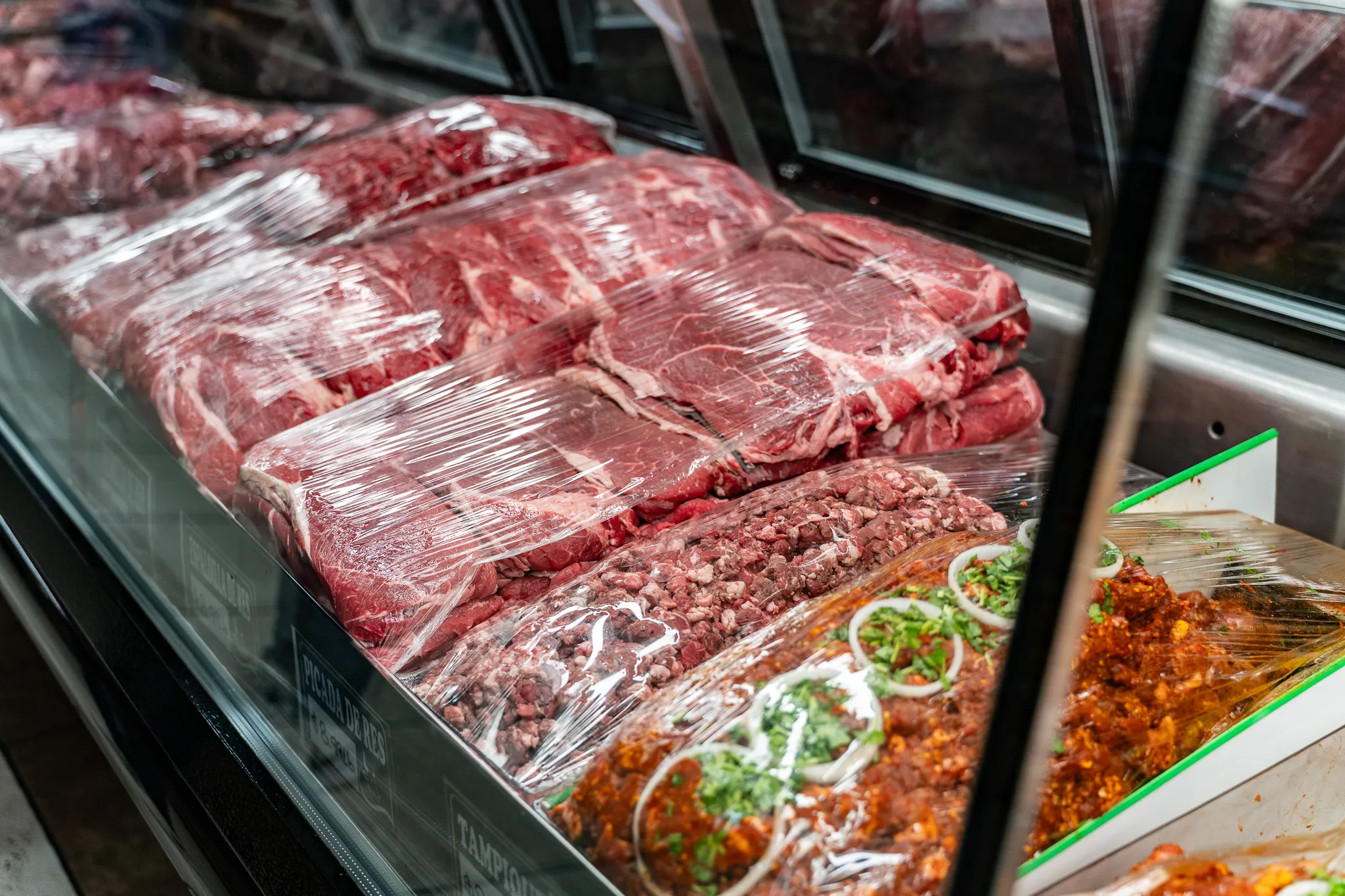 Fresh red cuts of beef and ground meat in the Carnicería 99 display case