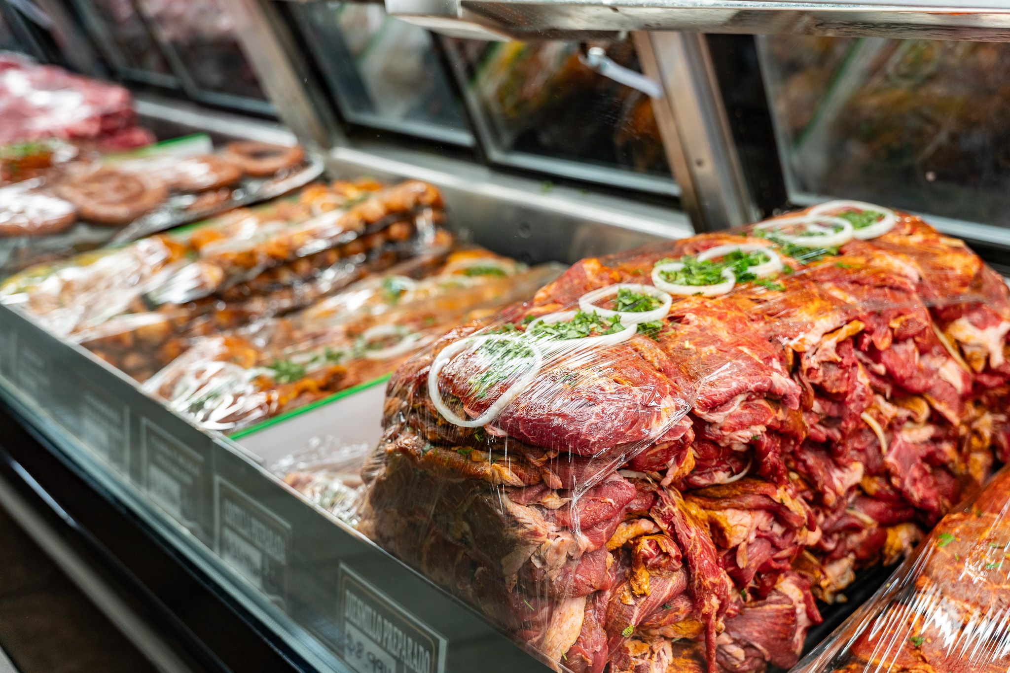 Close-up of house-marinated meats in the Carnicería 99 butcher case