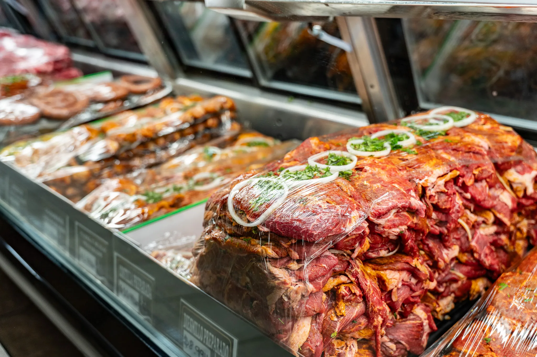 Close-up of house-marinated meats in the Carnicería 99 butcher case